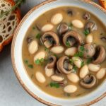 Creamy Mushroom White Bean Stew in a bowl with crusty bread on the side