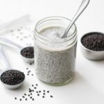 Basic chia pudding in a glass jar with measuring spoons of chia seeds nearby